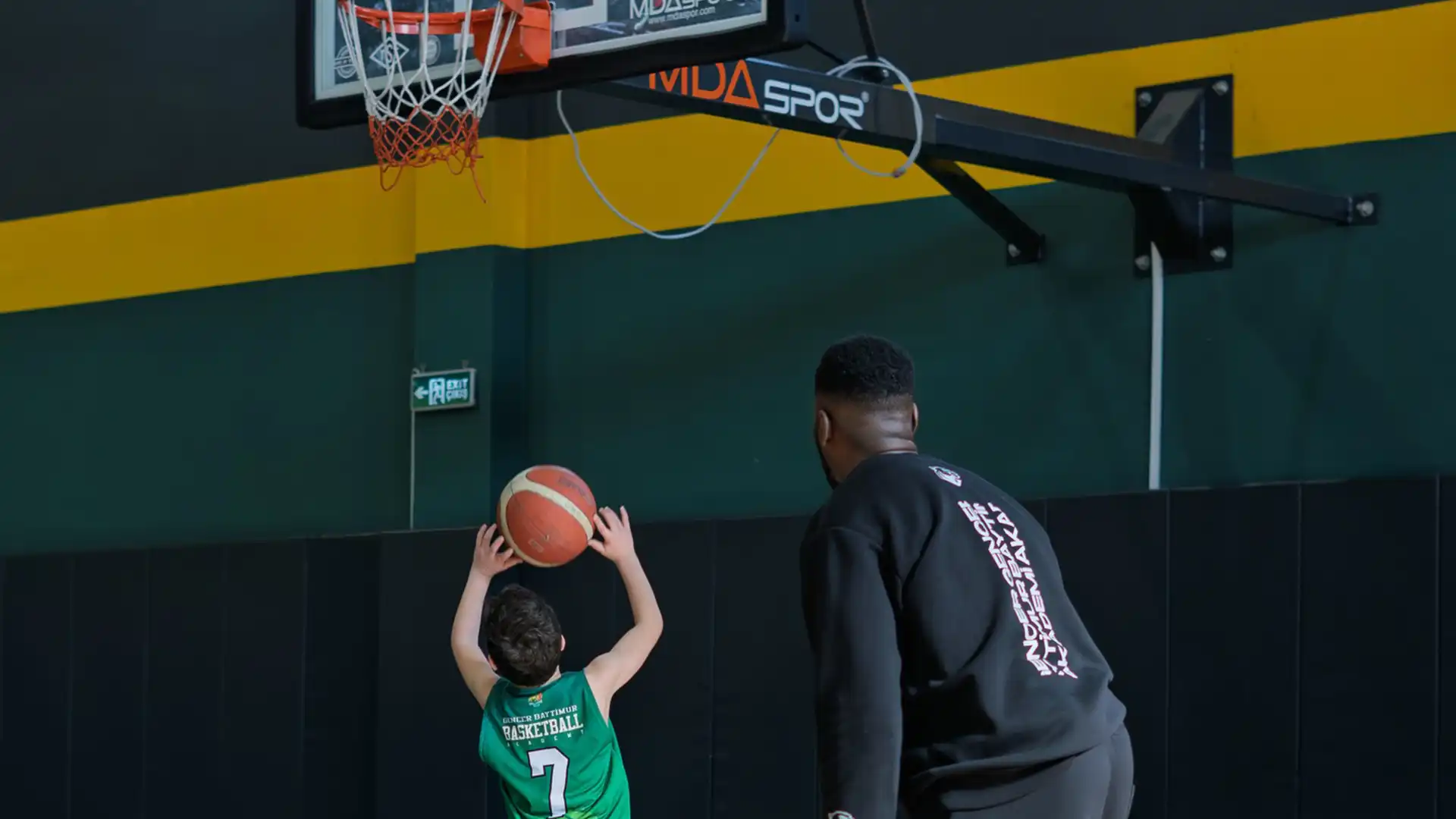 Ankara Basketbol Kursu ve profesyonel antrenör desteğiyle şut atışı pratiği yapan yeşil formalı genç sporcu